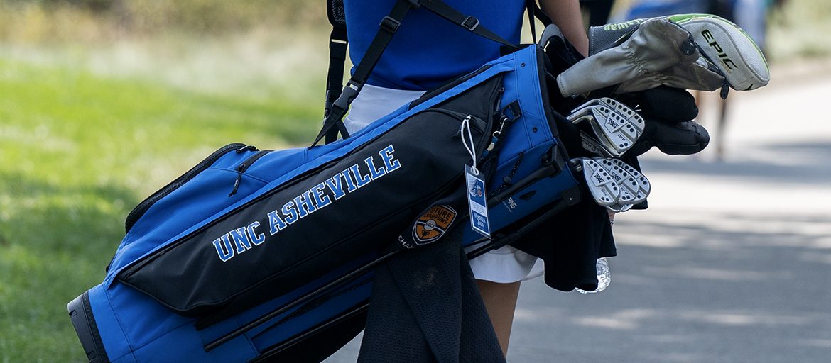 A person carrying a UNCA golf bag with equipment inside