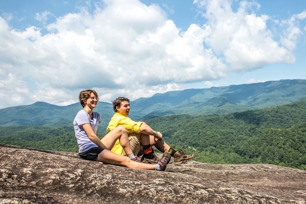 two students sitting on an exposed rock in the mountains