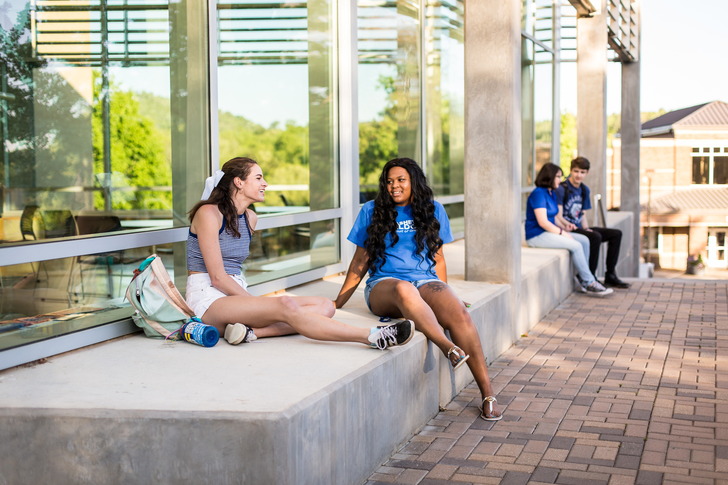 Two students sitting near the steps next to Rhodes Robinson Hall
