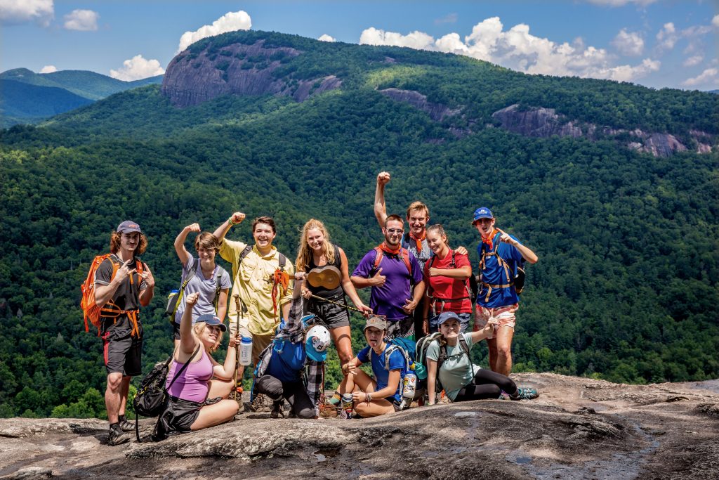 A hiking group posing at the top of a mountain