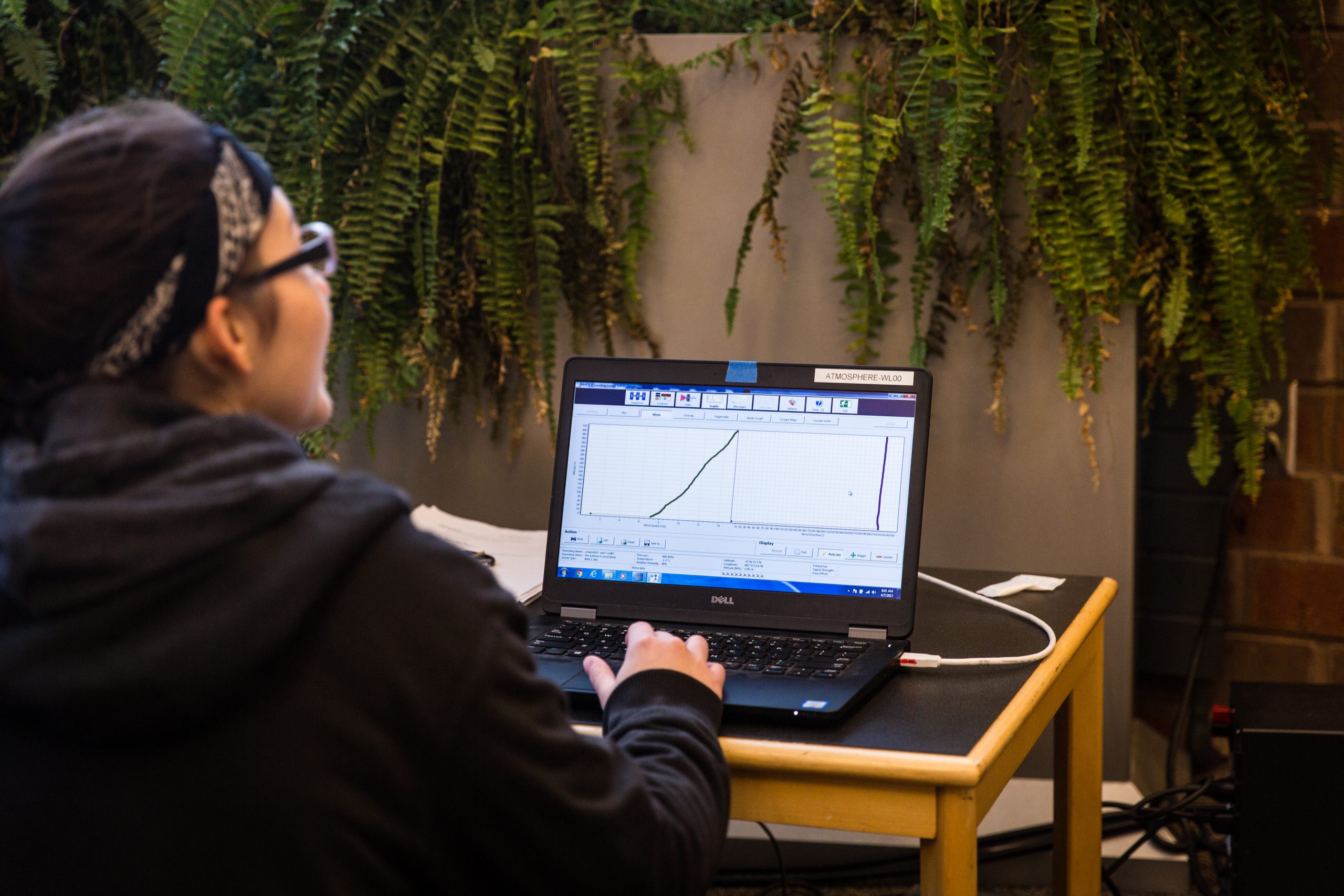 An atmospheric science student charting data on a laptop