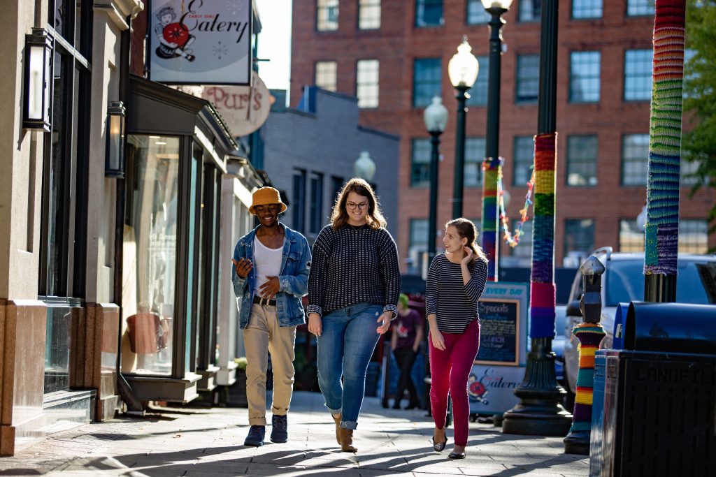 Three students walking down the sidewalk in downtown Asheville
