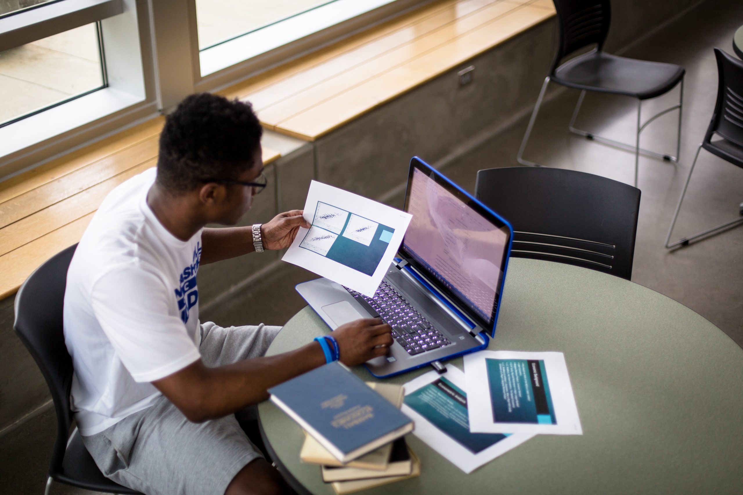 someone sitting at a laptop with study materials around them