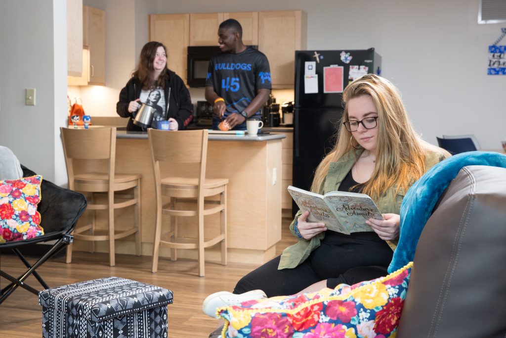 some students hanging out in a woods apartment shared living room and kitchen