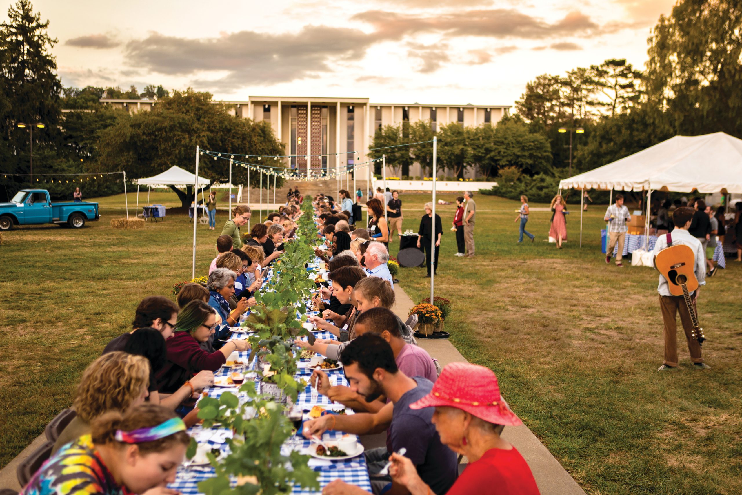 People sitting at a long table on the quad for the Farm to Table event, 2023