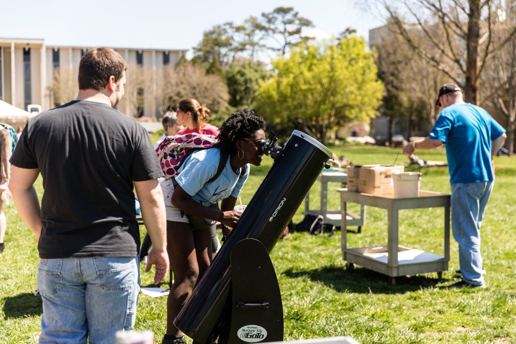Students looking through a telescope on the quad during the day