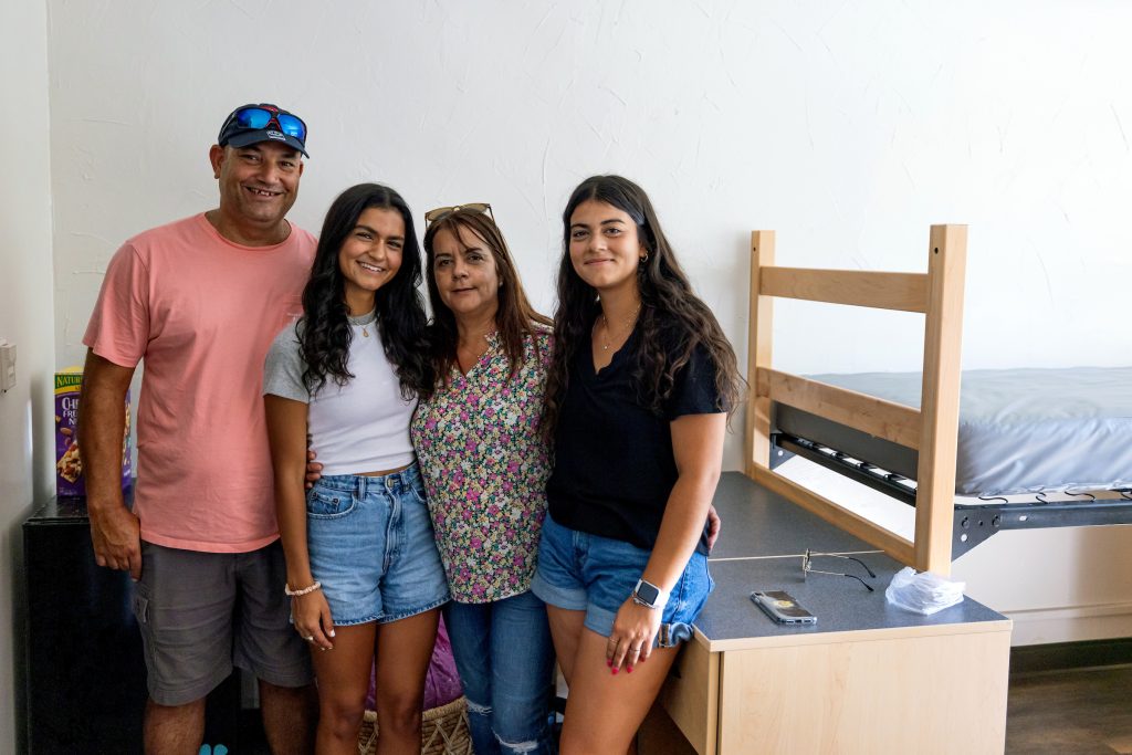 Student and parents standing in residence hall room unpacking during August 2023 Move-In.