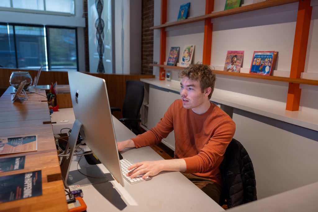 a student working at an iMac computer at a desk