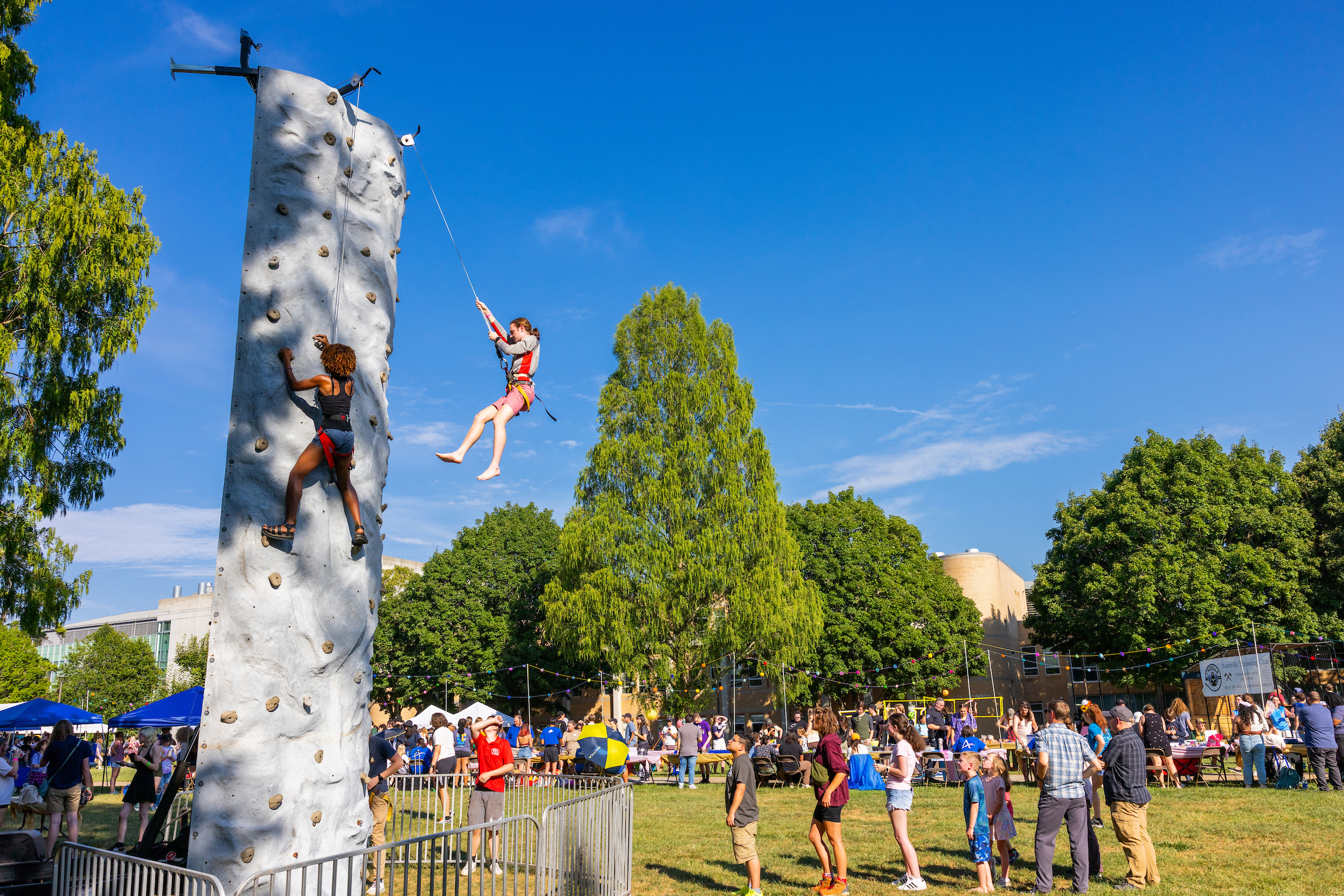 students rock climbing and standing in line on quad