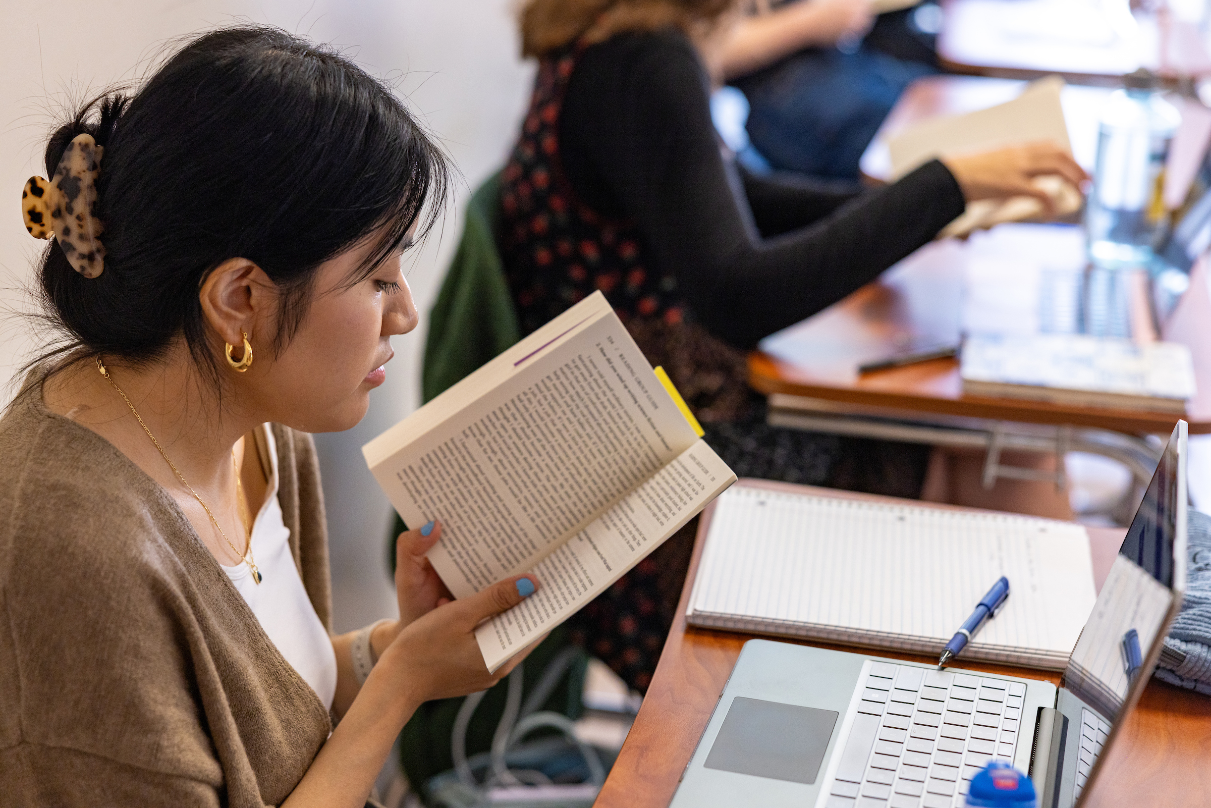 a student holding an open book in a class lecture